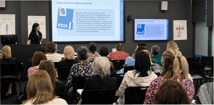 woman presenting to seated audience in conference room